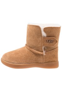 Bottines en daim beige avec une doublure intérieure douce, bout rond et semelle en caoutchouc, présentant un accent cousu et une étiquette de marque.