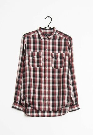 Long-sleeve button-up shirt with red, black, and white plaid pattern, two chest pockets with button flaps, hanging on black hanger.