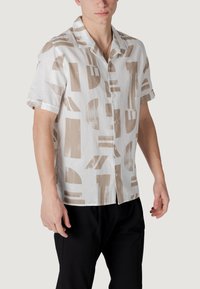 Korte mouw overhemd in witte linnen met abstracte beige patronen, met een kraag en een ontspannen pasvorm, gecombineerd met zwarte broek.