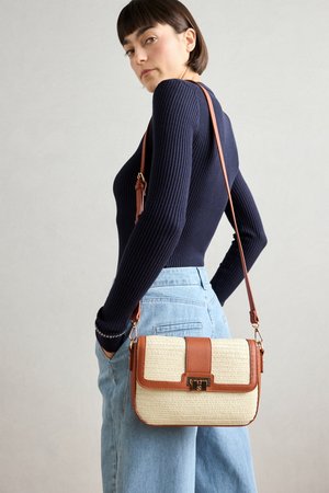 Sac en bandoulière en beige tissé avec des accents en cuir marron et des éléments en métal, de forme rectangulaire et avec une bandoulière réglable, porté à la taille.