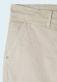 Pantalon beige en mélange de coton avec une texture lisse, doté d'une poche avant, de passants pour ceinture et d'un petit détail de bouton en métal.
