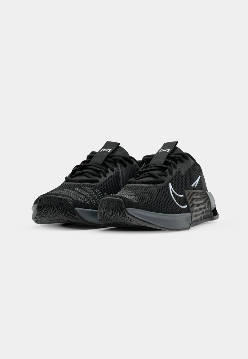 Baskets de sport noires avec une tige en mesh respirant, des accents texturés et un design de swoosh prominent. Semelle extérieure en caoutchouc avec un motif en zigzag.