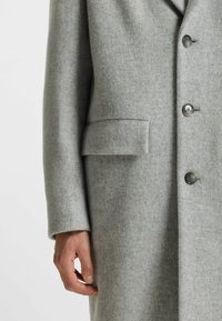 Cappotto di lana grigio chiaro con rever a tacca, quattro bottoni e tasca a patta. Presenta una texture liscia e maniche lunghe.