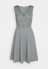 Hihaton mekko hillityssä vihreässä, jossa pitsinen yläosa ja levenevä hame. V-pääntie ja tasainen pehmeä pinta koko mekossa.