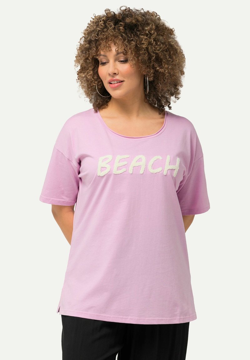 Rosa Kurzarmshirt mit dem Schriftzug "BEACH" in weißer, strukturierten Schrift, Rundhalsausschnitt und seitlichen Schlitzen für mehr Bewegungsfreiheit.