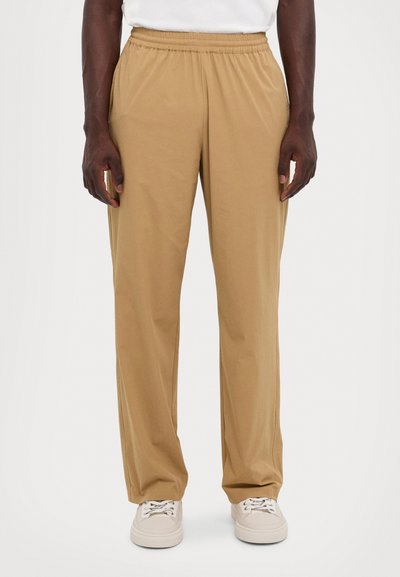 Beige bukse med elastisk liv, rett ben design, lett materiale, sidelommer, kombinert med kremfargede sneakers. Minimalistisk og nøytral fargepalett.