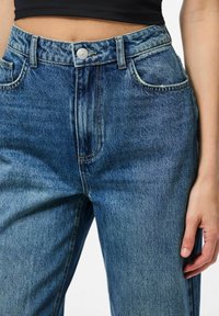 Traperice visokog struka u srednjem pranju, s pet džepova, srebrnim kopčanjem i laganim izbljeđivanjem tkanine.