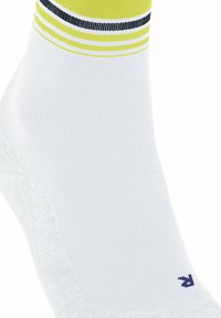 Biała skarpetka sportowa o prążkowanej strukturze, z żółtymi i granatowymi paskami na górze oraz małym granatowym logo z boku.