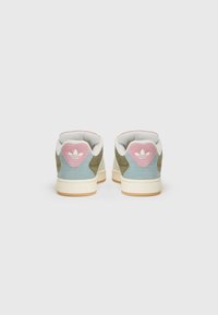 Des baskets avec un dessus texturé en bleu clair et vert olive, avec des accents roses au niveau du talon et une semelle en caoutchouc beige.