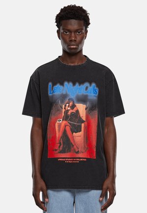 Schwarz oversized T-Shirt mit grafischem Druck einer sitzenden Figur in einem Kleid, mit dem Text "Late Night Calls" in blauen und roten Akzenten.