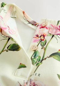 Virágos pamut blúz krémszínű alapon, pink és zöld rózsamintával. Arany színű, szív alakú gombokkal és belül látható címkével.