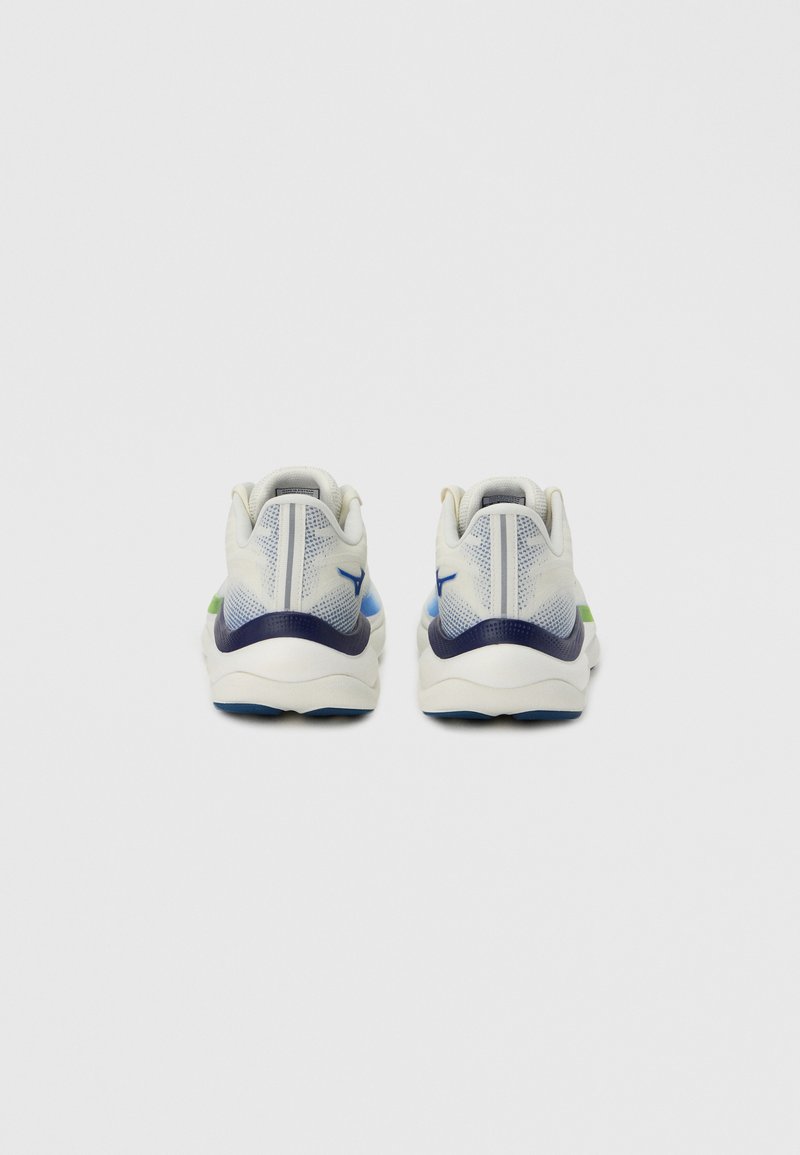 Zapatillas deportivas blancas con material de malla, forma redondeada, detalles en azul y verde, y un panel trasero texturizado para mayor estabilidad.