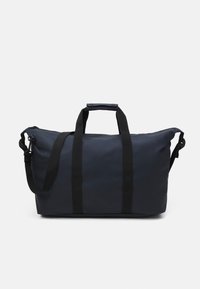 Námornícky duffel batoh vyrobený z vodoodpudivej tkaniny, s dvoma čiernymi rukoväťami, nastaviteľným ramenným popruhom a dvojitým zipsom.