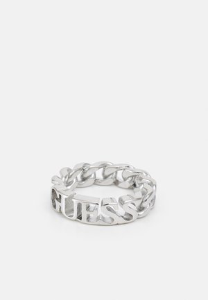 Anneau chaîne en argent avec un design lié intégrant le mot "GUESS" dans la bande sur un fond clair uni.