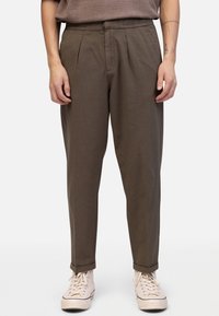 Khakikleurige taps toelopende broek met elastische tailleband, voorplooien en opgerolde boorden, gecombineerd met lichtbeige schoenen. Gladde katoenmixstof.