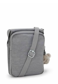Bolso cruzado gris hecho de un tejido suave, con cierre de cremallera, correa ajustable y un detalle de pompón suave en el lado.