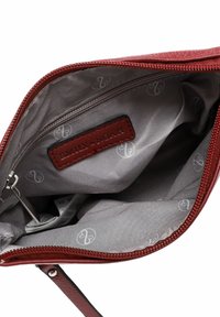 Rotes Leder-Zipperetui mit strukturiertem Äußeren. Das Innere verfügt über ein graues Futter mit einem subtilen Logo-Muster und einem markierten Lederanhänger.