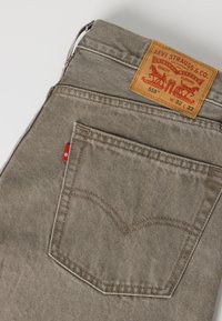 Γκρι τζιν Levi's με πίσω τσέπη που έχει ραμμένο τόξο και δερμάτινη ετικέτα με μέγεθος W32 L32 στη μέση.