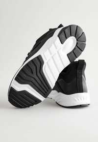 Black athletic shoes with a mesh upper, featuring a padded collar, textured black sole, and white midsole with detailed tread patterns.