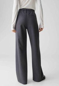 Wijd uitlopende broek in donkergrijze stof met elastische tailleband en twee achterzakken, met een gladde textuur en een op maat gemaakte uitstraling.