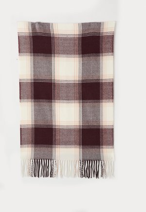 Couverture à carreaux présentant un bordeaux profond, de la crème et du gris avec des bords frangés, suspendue contre un fond blanc.