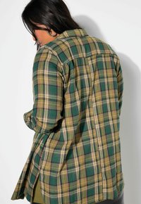 Groene en gele geruite shirt gemaakt van stof met een zachte textuur. Kenmerkt zich door een knoopsluiting en zijopeningen voor comfort.
