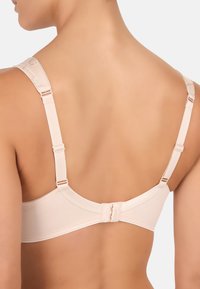 Beige bh med justerbare stropper, hægtemechanisme, blødt stof, sømløs design og glat tekstur. Bagside viser strap-detaljer.
