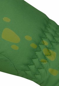 Grüner Stoff in verschiedenen Farbtönen mit glatter Textur. Dekorative Akzente bestehen aus helleren organischen Formen und Zickzack-Stichen.