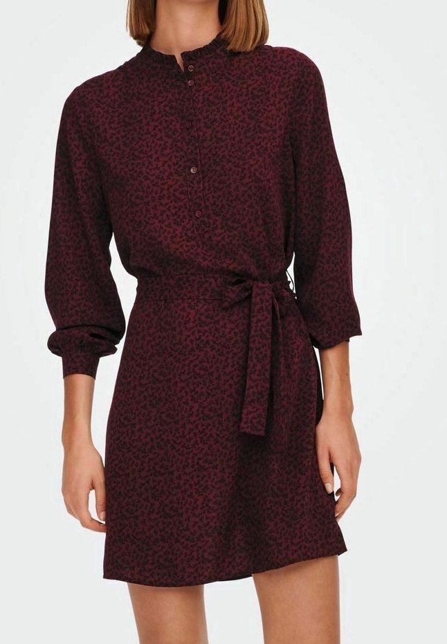 Femme portant une robe bordeaux à manches longues avec un motif noir subtil, boutonnée à l'avant et une ceinture nouée à la taille.
