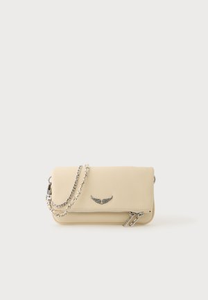 Sac bandoulière en cuir couleur crème, doté d’une bandoulière chaîne argentée, d’un emblème en forme d’aile et de détails zippés, sur un fond uni.