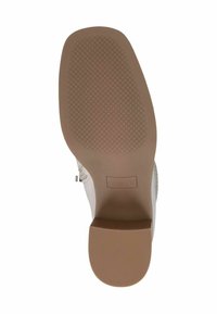 Sole di scarpa bianca con un motivo in gomma testurizzata, caratterizzata da una intersuola beige. Include un'etichetta del marchio sul lato inferiore. Design complessivo piatto.