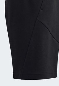 Pantaloni sportivi neri realizzati in tessuto morbido, con cuciture angolate e una texture liscia. Nessuna tasca visibile o dettagli in metallo.