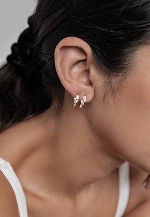 Goldfarbene Ohrringe mit drei blattförmigen Designs, die mit klaren Kristallen verziert sind und eine zarte und kunstvolle Anordnung zeigen.