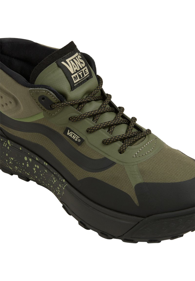 Grüne und schwarze Vans MTE Sneaker mit einer strukturierten Oberseite, Schnürverschlüssen und einem gesprenkelten Sohlendesign. Hochschnitt-Stil mit gepolsterter Knöchelmanschette.