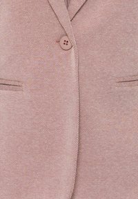 Blazer rosa claro con textura, que presenta solapa con muesca y dos bolsillos frontales, asegurado con un cierre de botón en un tono a juego.