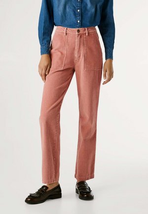 Pantaloni in corduroy rosa tenue con righe verticali, design a vita alta e tasche anteriori. Abbinati a una camicia di jeans scura e mocassini.