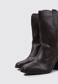 Brown leather ankle boots with pointed toes, smooth texture, slight heel, and decorative stitching on the shaft.