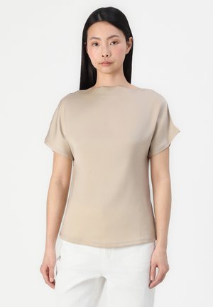 Beige kortermet topp med båtutringning og glatt, lett stoff. Har en avslappet passform og subtil glans.