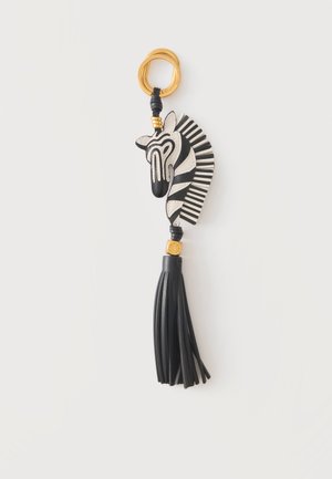 Nøglering med sort og hvid zebrahoved-design, guld ring og sort læderkvast, der hænger under zebraen.