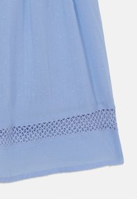 Robe en tissu bleu clair avec des pois en relief et un panneau en dentelle décorative à l'ourlet. Texture douce et lisse avec un design fluide.