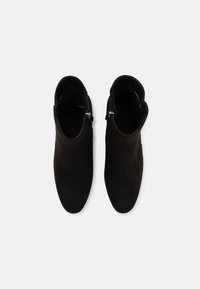 Botines de ante negros con una textura suave, que presentan un cierre de cremallera en un lado y un diseño de punta redondeada.