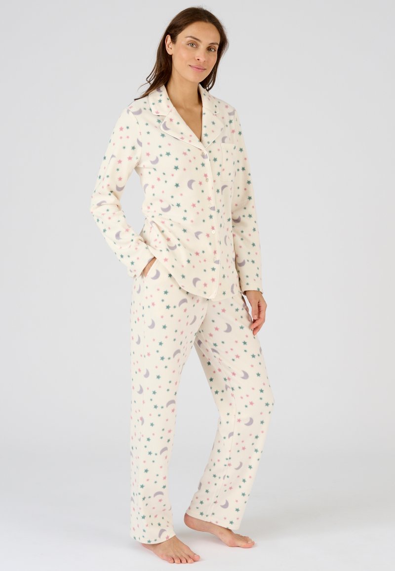 Fleece pyjama set in roomkleur met een patroon van sterren en manen in roze, groen en grijs. Heeft een gekraagde bovenkant met knopen en een broek.