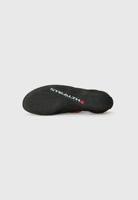 Crna potplat za penjačke cipele s teksturiranom površinom, s crvenim detaljem i oznakom "STEALTH C4". Zakrivljen, ergonomski oblik za performanse.
