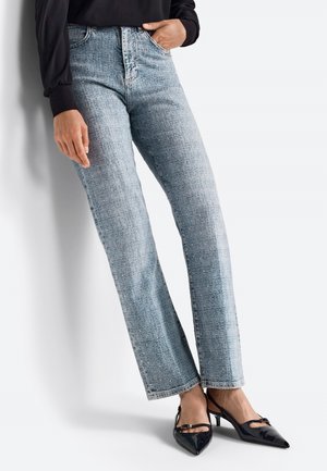 Jeans di denim azzurro chiaro a vita alta con gamba dritta e una texture sottile. Abbinati a tacchi in pelle verniciata nera con un fiocco decorativo.