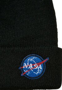 Čierny pletený čiapka s kruhovým modrým vyšitým logom NASA a červeným šikmým pruhom cez neho. Mäkká textura s hrubým rebrovaným dizajnom.