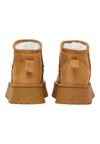 Braune Wildleder-Ankle Boots mit Fellfutter, runder Zehenform und einer dicken, strukturierten Gummisohle. Verfügt über eine hintere Zuglasche für einfaches Anziehen.