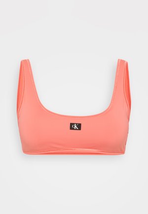 Sutien desportivo coral com um decote quadrado e alças largas. Feito de um material suave e elástico, apresentando um patch central preto com o logótipo.