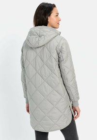 Grau gesteppte Jacke mit Kapuze, langen Ärmeln, seitlichen Schlitzen und gerippten Bündchen. Glatte Textur mit einem durchgängigen Rautenmuster.