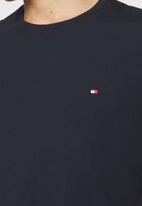 Mørkeblå bomulds t-shirt med rund halsudskæring og korte ærmer. Har et lille broderet logo i rød, hvid og blå på brystet.
