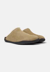 Pantofole in suede color sabbia con morbida fodera in shearling bianco e suole in gomma nera. Design elegante con chiusura sul retro per un facile utilizzo."